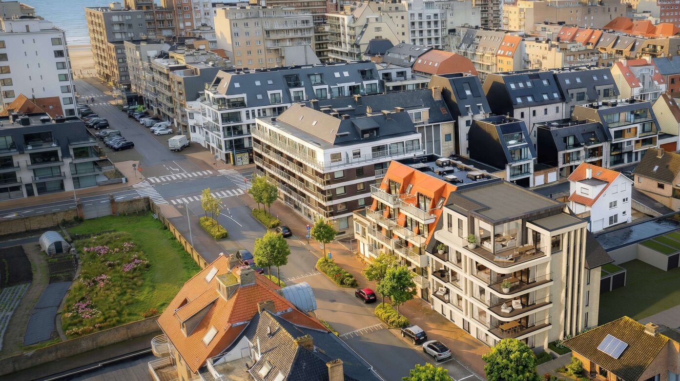 Modern appartementsgebouw met grote terrassen, glazen balustrades en eigentijdse architectuur langs een rustige straat.