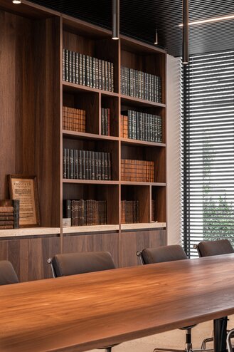 Straatzicht van het notariaat in Meulebeke, ontworpen door GC Architecten: een licht gekleurd volume met verticale gevellamellen, donkere raamkaders en een lagere zijvleugel, omgeven door een strakke haag en siergrassen.