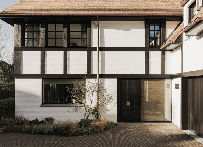 Exterieurbeeld van inkom met oprit in klinkers, donker vakwerk van karaktervolle villa in Knokke door GC Architecten | © Bert Demasure