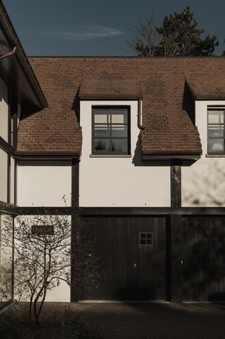 Karaktervolle villa in Knokke door GC Architecten met zicht op garagepoort met donker hout, roodbruine pannen, vakwerk | © Bert Demasure