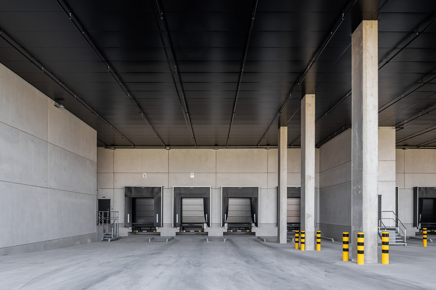 Interieur van een laadzone met meerdere laadkades en betonstructuur in een logistiek bedrijfsgebouw | © Michiel Vergauwe