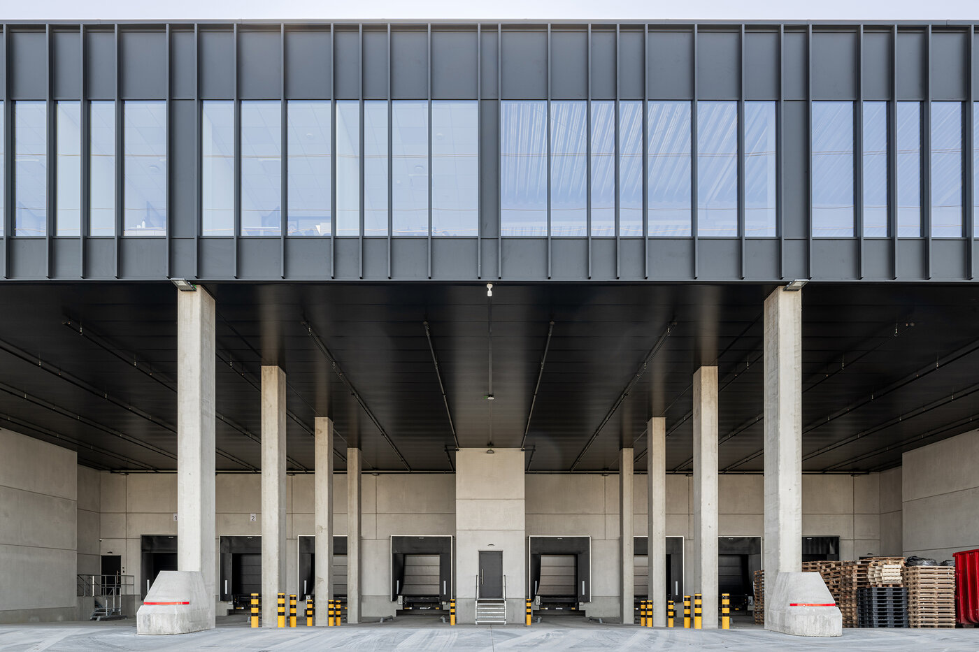 Exterieur van een overdekte laadzone met betonkolommen en laadkades bij een bedrijfsgebouw | © Michiel Vergauwe