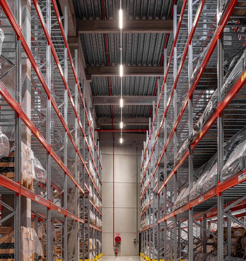 Interieur van een logistiek magazijn met hoge palletstellingen en brede circulatiegang in een bedrijfsgebouw in Oudenaarde | © Michiel Vergauwe