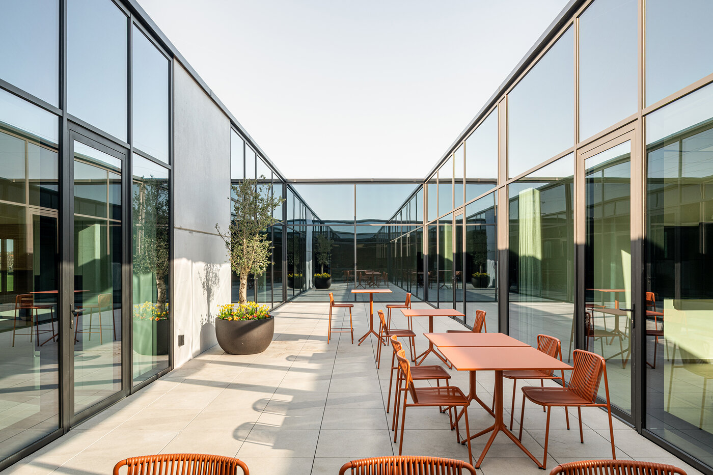 Binnenpatio met terraszitplaatsen en glazen gevels die zorgen voor licht en connectie in een bedrijfsgebouw | © Michiel Vergauwe