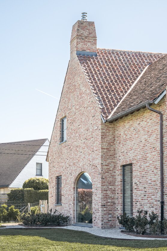Zijgevel met hoge bakstenen schouw en rondboog raam van landelijke woning