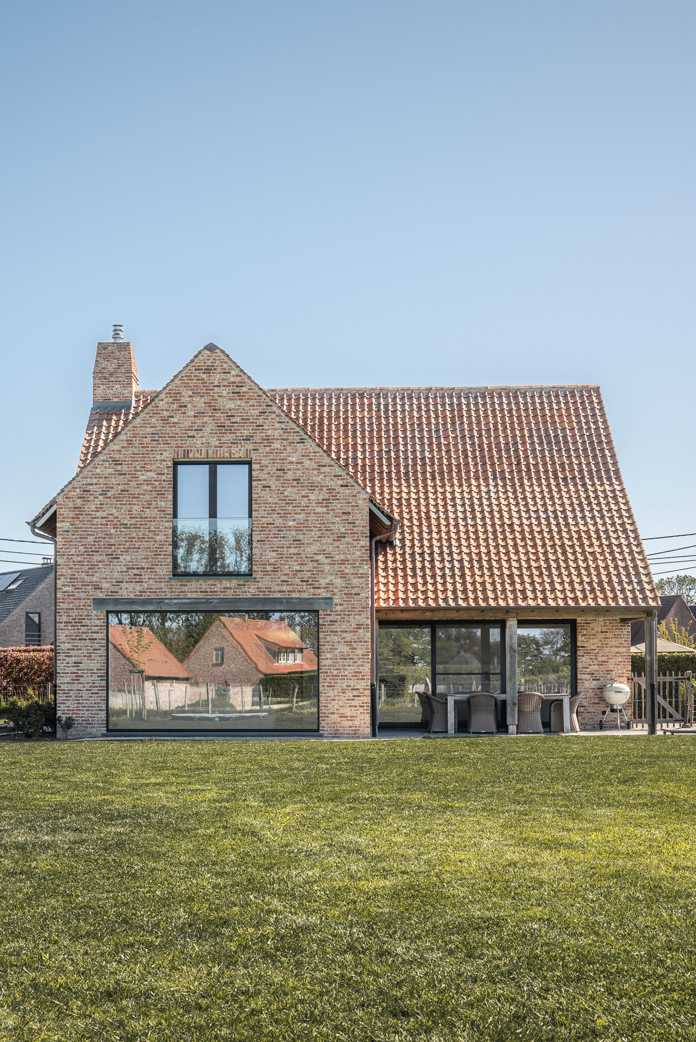 Tuinzijde met groot schuifraam en overdekt terras van bakstenen woning