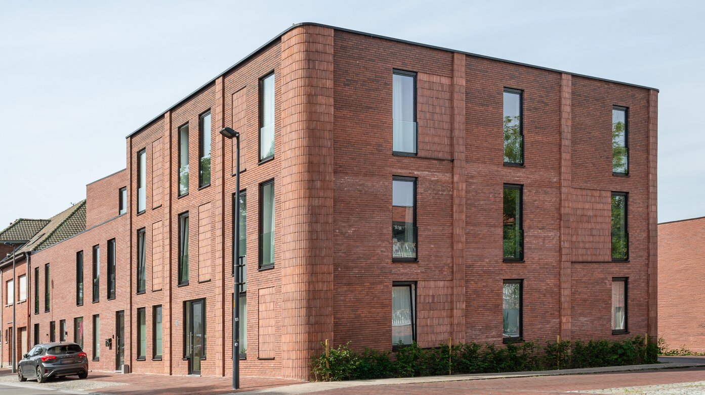 Hedendaags appartementsgebouw van GC Architecten met afgeronde bakstenen hoek en gevarieerde raamritmiek