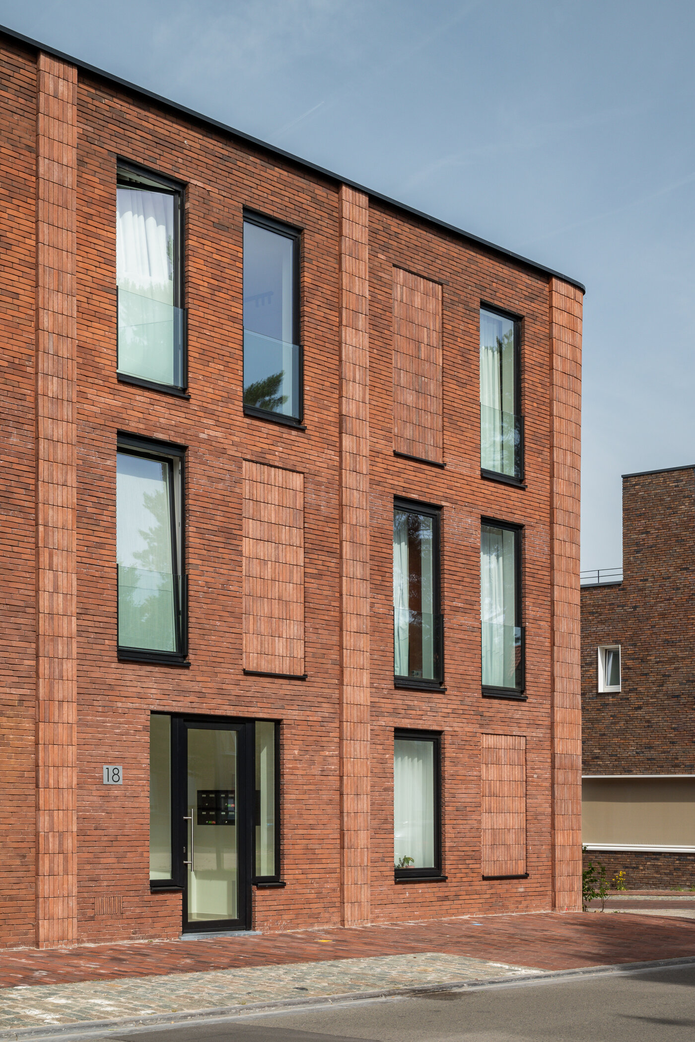 Moderne meergezinswoning van GC Architecten met roodbruine bakstenen gevel en hoge ramen