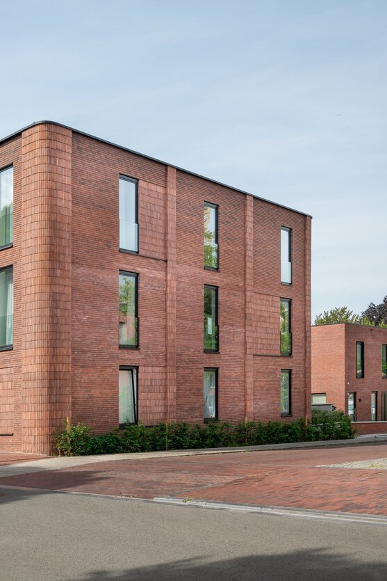 Straatgevel van hedendaags appartementsgebouw met ritmische verticale ramen en bakstenen gevel