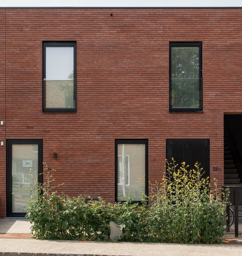 Inkomgevel van een hedendaagse woningen van GC Architecten met roodbruine baksteen en zwarte raamprofielen