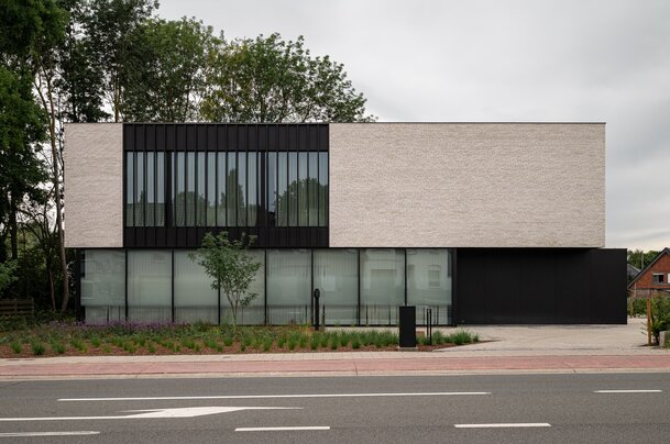 Hedendaags kantoorgebouw met minimalistische architectuur, lichte gevelsteen en grote glaspartijen.